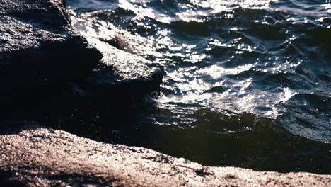 Close up of sea splash by coast. Crashing ocean waves on rocks.