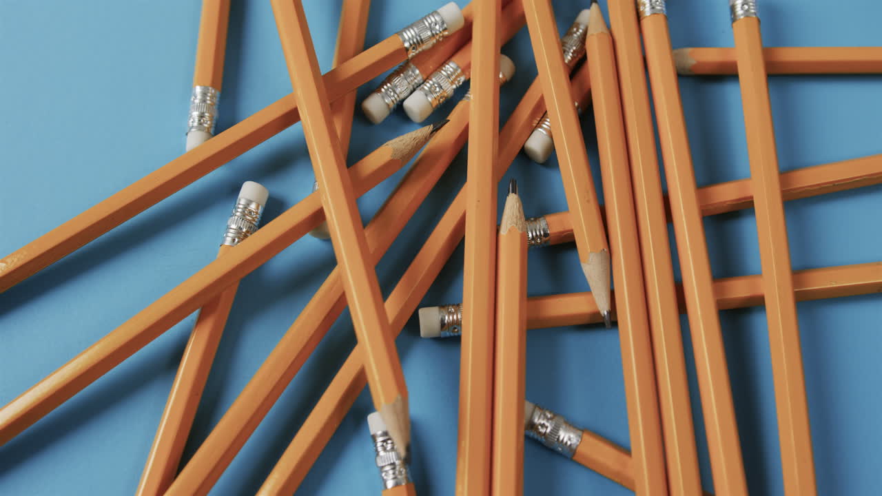 vista aérea de lápices dispersos con fondo azul, en cámara lenta