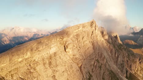 filmische drohnenaufnahme, die einen riesigen leuchtenden steilhang des berges cinque torri in italien bei sonnenlicht zeigt