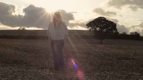 Woman-walking-across-farm-land-field-of-oats-after-harvest-in-sunshine-1