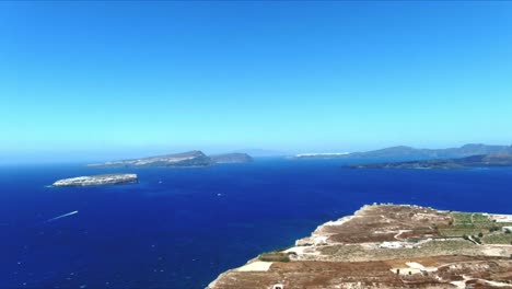 aerial 4k blue sea and sky top view of village of akra mavro vouno with oia in distance in santorini greece