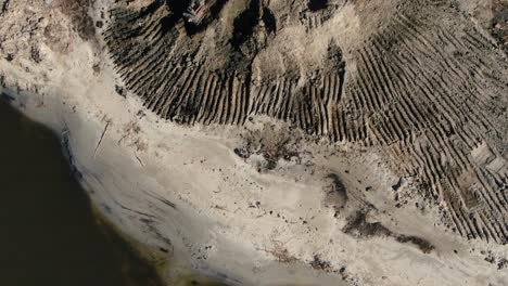 Top-down-drone-shot-of-excavator-near-the-shore