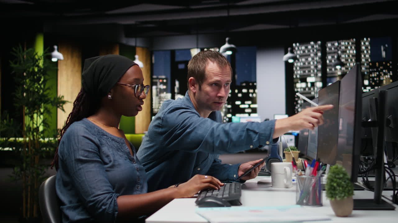 Diverse Coworkers Collaborating on Computer Project in Modern Office at Night