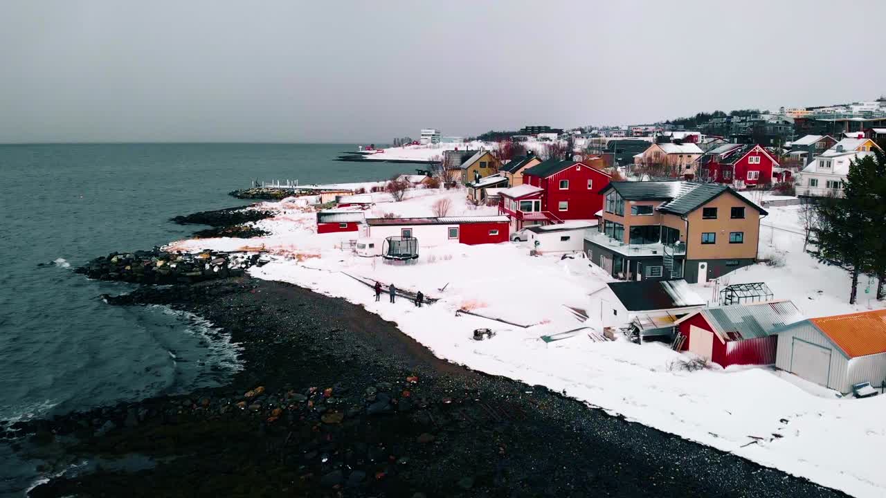 Aerial view of houses, traditional architecture at the sea, in the Fagereng neighborhood, dark, cloudy, winter day, in Troms city, Nordland, Norway - rising, drone shot