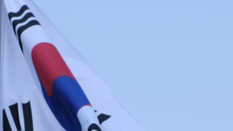 a waving south korean flag in daylight and in slow-motion with a clear blue sky on the background