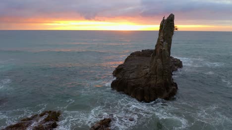 Neigeaufnahme-Von-Domfelsen-Und-Wirbelndem-Ozean-Mit-Dramatischem-Sonnenuntergang-Im-Hintergrund-In-New-South-Wales,-Australien---Luftaufnahme