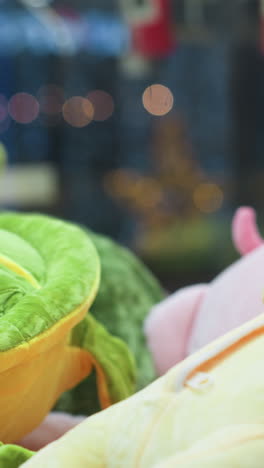 primer plano de juguetes de peluche vibrantes con animales de peluque amarillos y verdes en la máquina de garras de arcade, con luces de colores borrosas en el fondo y reflejos sutiles