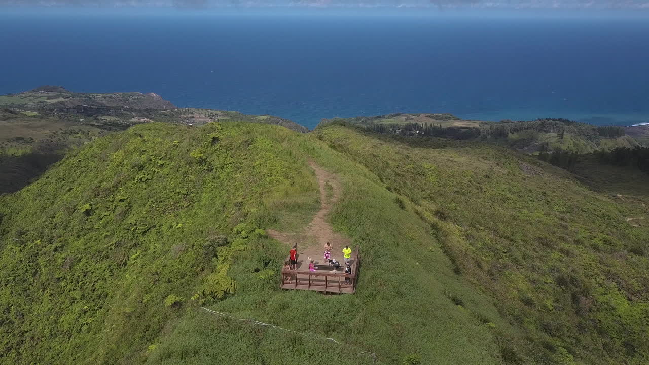 Tourists on lookout point at top of mountain with beautiful blue ocean in the background