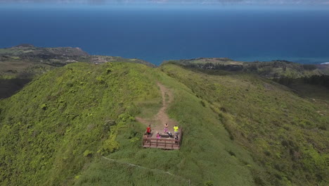 tourists on lookout point at top of mountain with beautiful blue ocean in the background