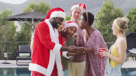 Happy-group-of-diverse-friends-using-smartphone-at-christmas-party-in-garden