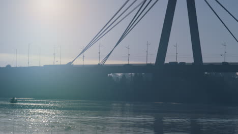 Moderne-Stadtbrücke-Beleuchtetes-Abendsonnenlicht.-Wasseroberfläche,-Die-Die-Straße-Reflektiert.