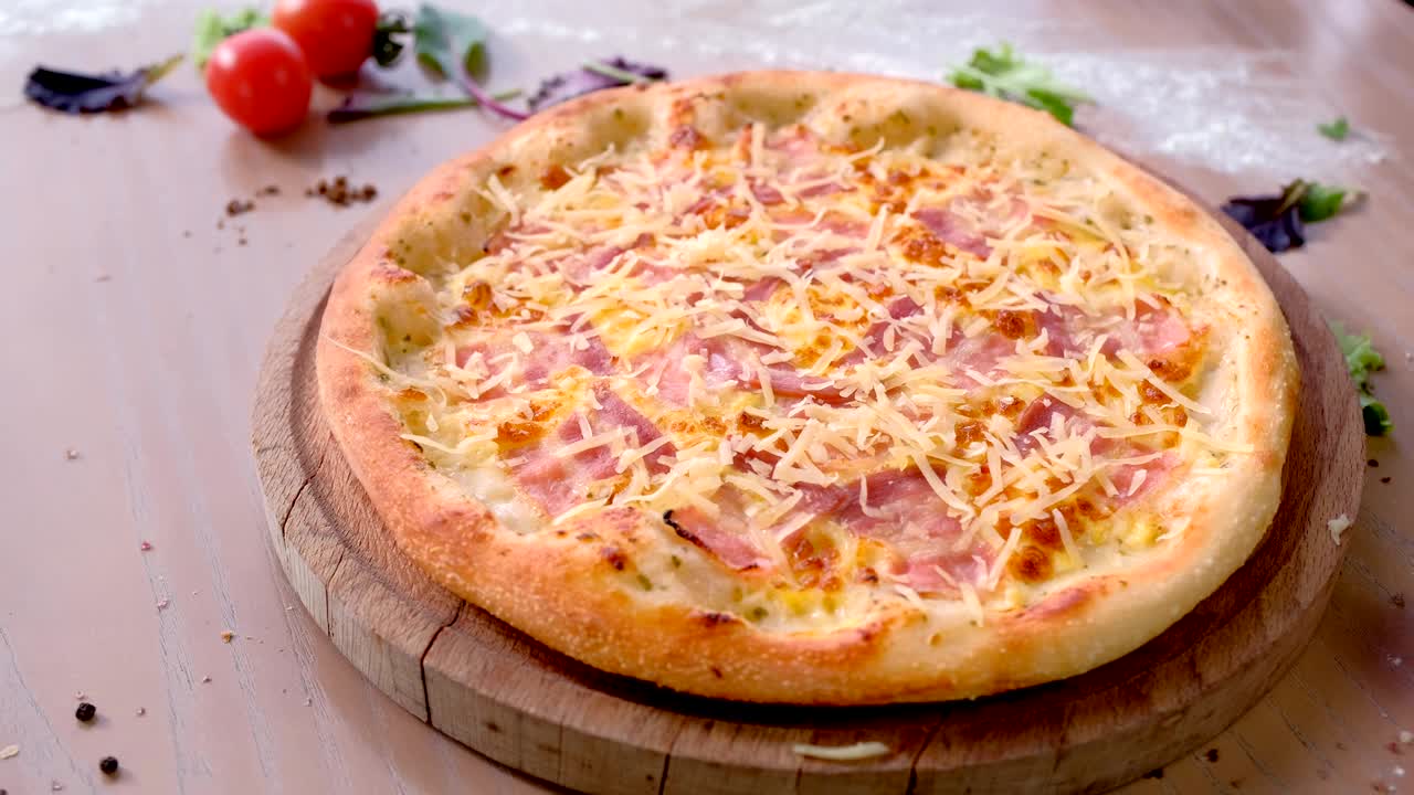 테이블 위에 나무판에 베이컨과 치즈를 은 피자.