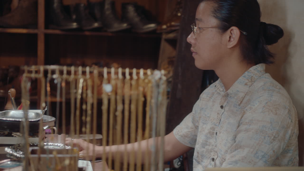 Asian Man Using Computer in Antiques Store or Pawn Shop