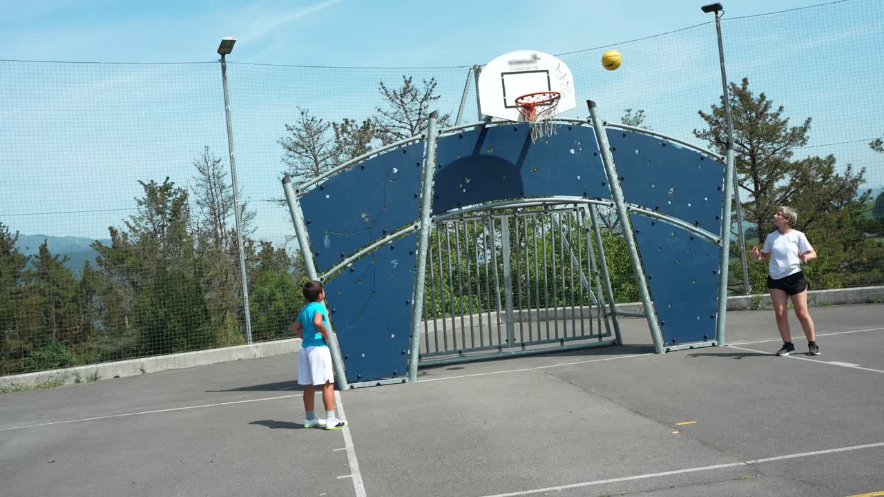 Ragazzo e donna giocano a basket su un campo all'aperto