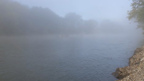 misty morning on the river: fishermen in a foggy river scene