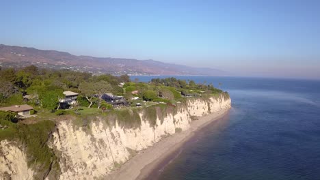 breathtaking 4k aerial drone shot of mansions in malibu, california overlooking the cliffs with the pacific ocean and santa monica mountains in the background