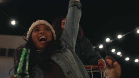 beautiful young woman having fun sitting in shopping cart group of friends enjoying crazy rooftop party at night playfully celebrating weekend