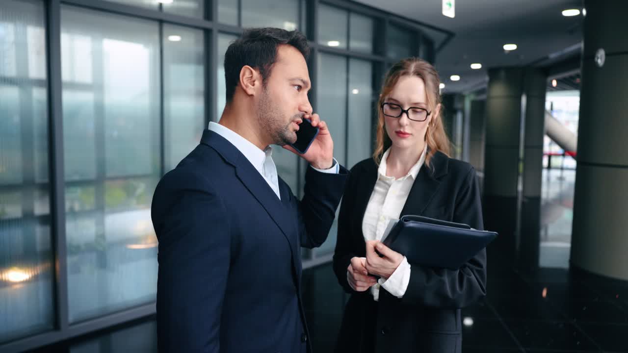 In slow motion, a desperate businessman gets bad news on a phone call and shakes his head in disappointment to his anxious colleague, showing a business failure