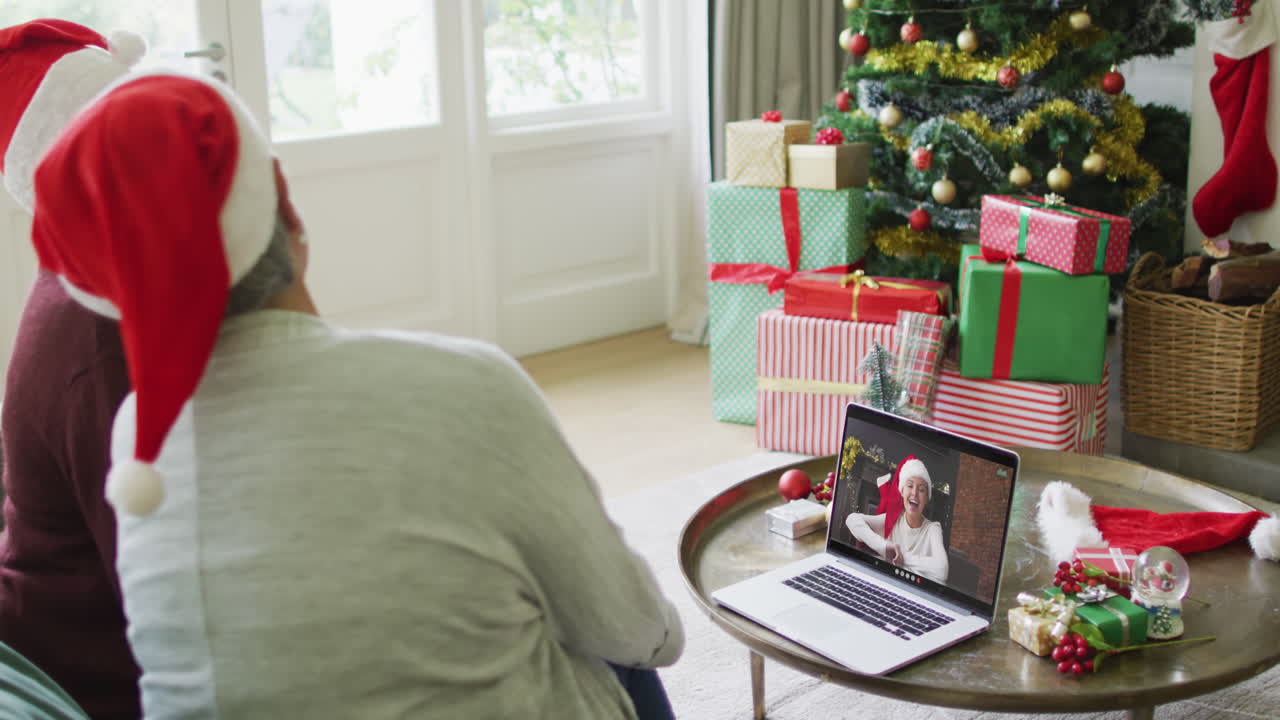 diversas amigas mayores que usan una computadora portátil para una videollamada de navidad con una mujer feliz en la pantalla