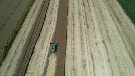 Top-Down-View-Of-A-Wheat-Harvester,-Surrounded-By-Yellow-And-Green-Fields-With-A-Clear-Blue-Sky-In-The-Background