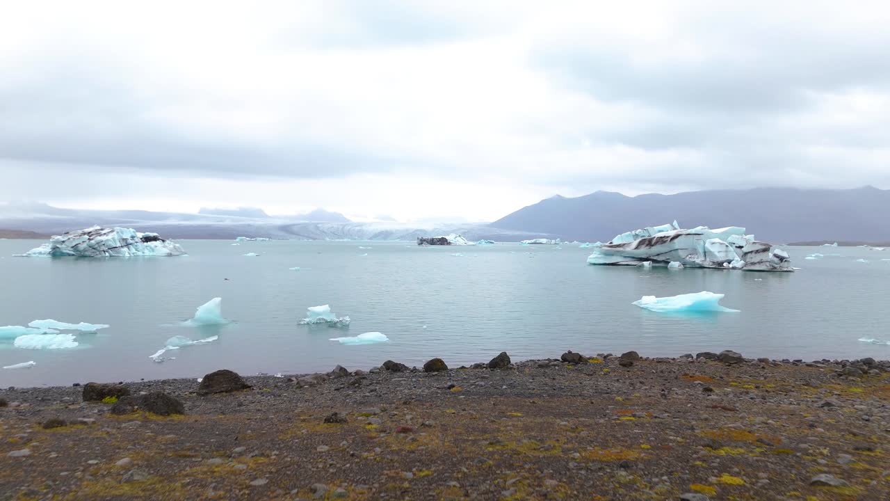 아이슬란드 의 호수 에서 녹는 빙산 을 바라보는 관광객 을 지나가는 공중 도리