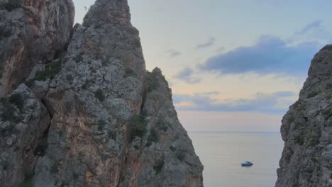 tiro lateral de drones que revela el mar mediterráneo y barcos detrás de formaciones rocosas puntiagudas en sa calobra, mallorca, españa