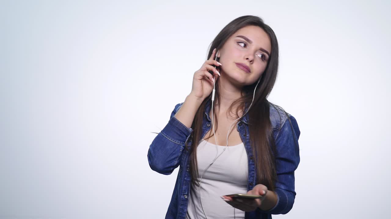 una joven feliz sonriente escuchando música con auriculares y bailando aislada sobre un fondo blanco
