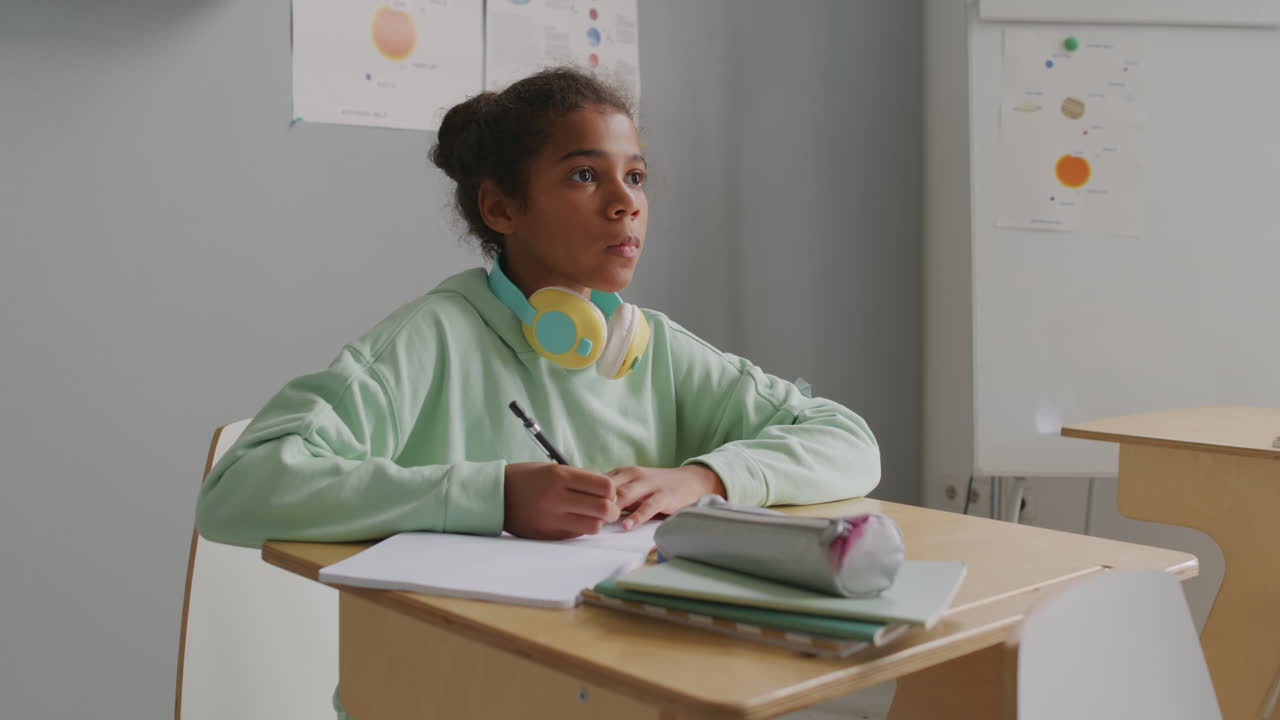Focused Girl Writing in Notebook during Lesson