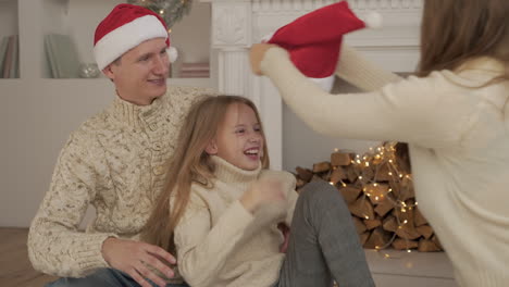 familia feliz ríe y juega con el sombrero rojo de santa