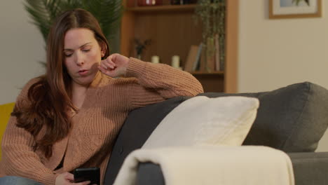 woman sitting on sofa at home using mobile phone to check social media message and scrolling online 1