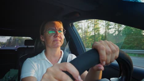 woman driving a car on a highway at sunset