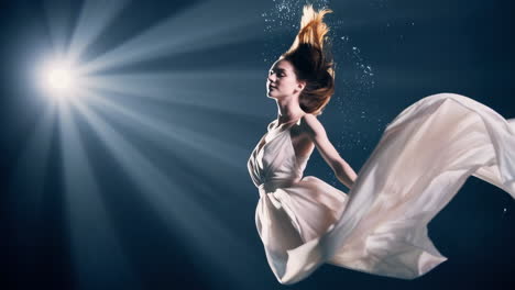 ethereal woman in flowing white dress underwater with light rays