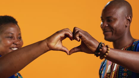 Ethnic-couple-in-love-showing-heart-shape-sign-and-kissing