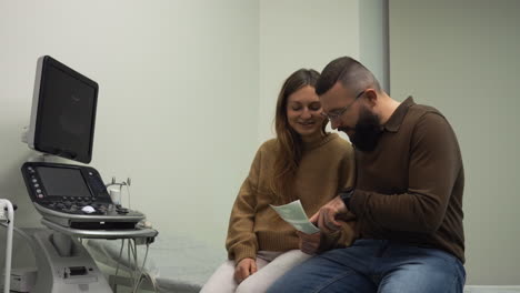 una pareja feliz mirando la imagen de su futuro hijo.