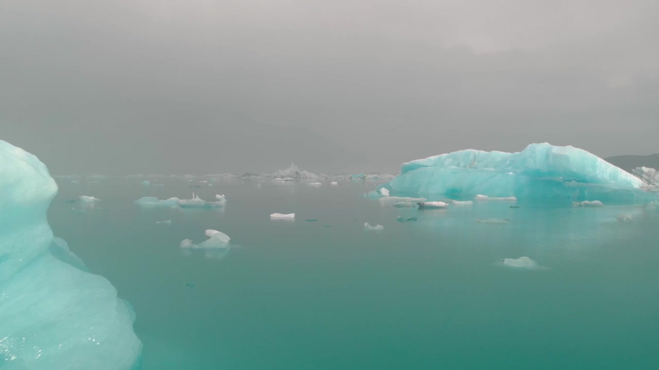 灰濛濛天空下的碧綠冰川湖與冰山
