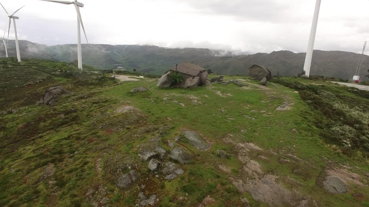 풍력 터빈이 있는 녹색 산에 있는 시골집