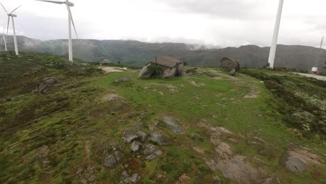 country house on green mountain with wind turbines