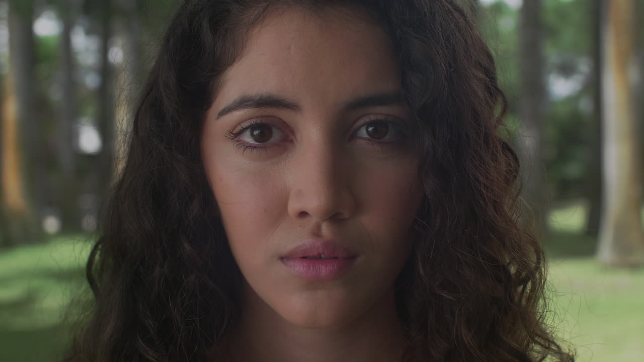 High-quality 4K footage of a serene young woman with curly hair and closed eyes. Shot outdoors in soft, natural light. Ideal for mindfulness, meditation, and wellness advertising