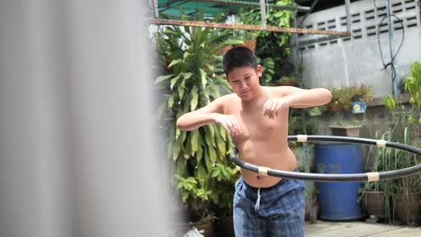 un chico gordo jugando al hula hoop en el patio trasero, en cámara lenta con el vientre moviéndose.