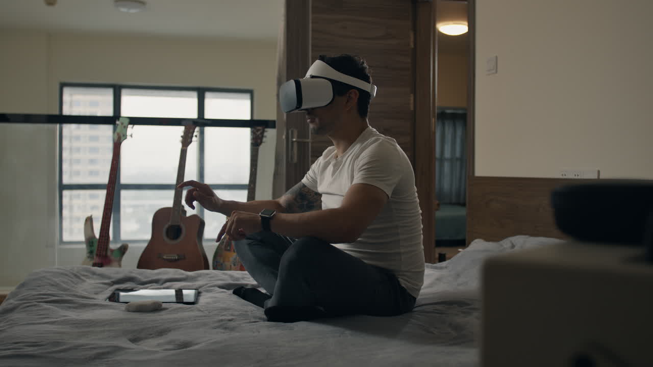 Person enjoying virtual reality at home, sitting on bed with VR headset