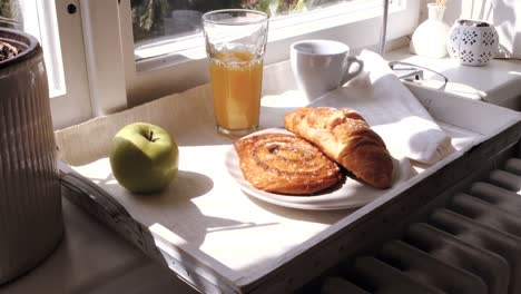 primer plano de croissant y un vaso de jugo en una bandeja