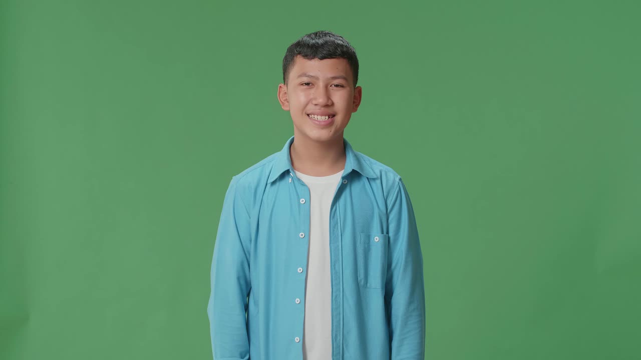 Young Asian Boy Warmly Smiling On Green Screen Background In The Studio