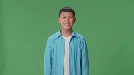 young asian boy warmly smiling on green screen background in the studio