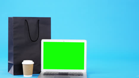 Shopping-bag,-disposable-coffee-cup-and-laptop-on-blue-background