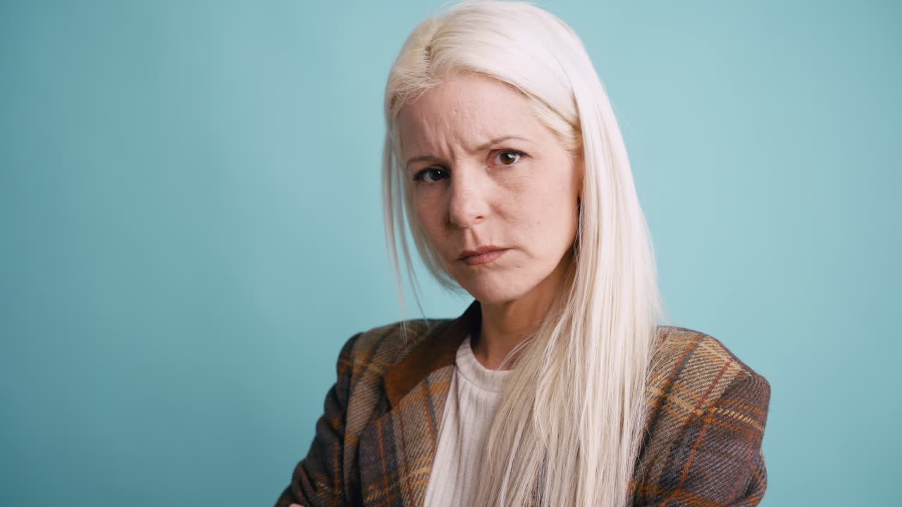 Donna bionda scettica con espressione seria su sfondo blu