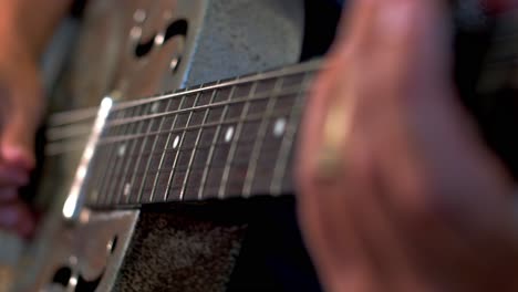 Man-Playing-Old-Metallic-Resonator-Guitar-with-Slide-Close-Up-Neck-Shallow-Focus