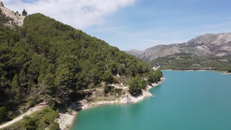 take off over an amazing turquoise lake and mountains in guadalest, spain