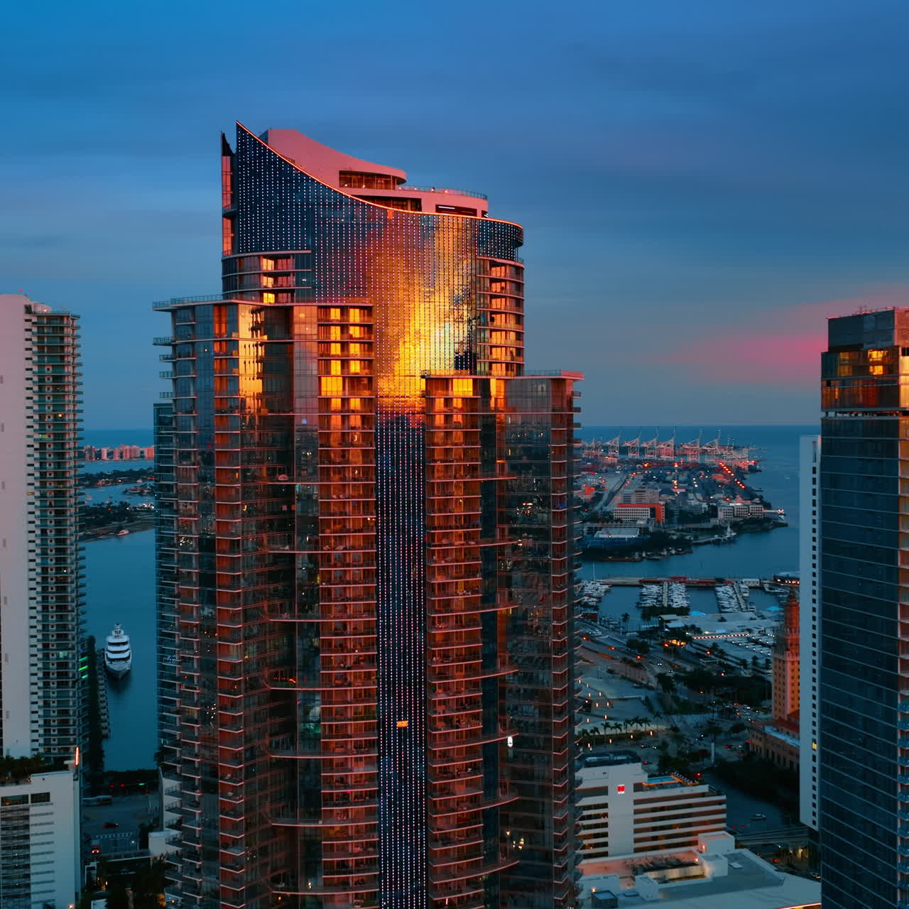 Golden light of setting sky reflects in the mirror windows of skyscrapers. Stunning view of Miami Beach architecture from aerial view.