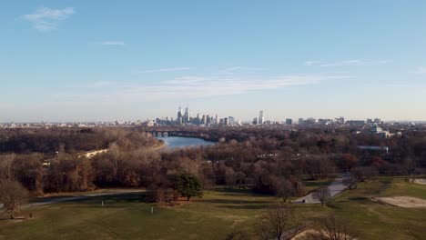 aerial drone shot, drone flying over some treetops towards the philadelphia skyscraper skyline, pennsylvania