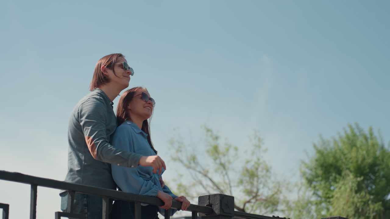 아름다운 다리 풍경에서 포옹하는 로맨틱한 커플, 수평선을 바라보며 행복한 시간을 보내는 행복한 커플, 다리 위에서 희망찬 표정으로 진심 어린 순간을 나누는 커플